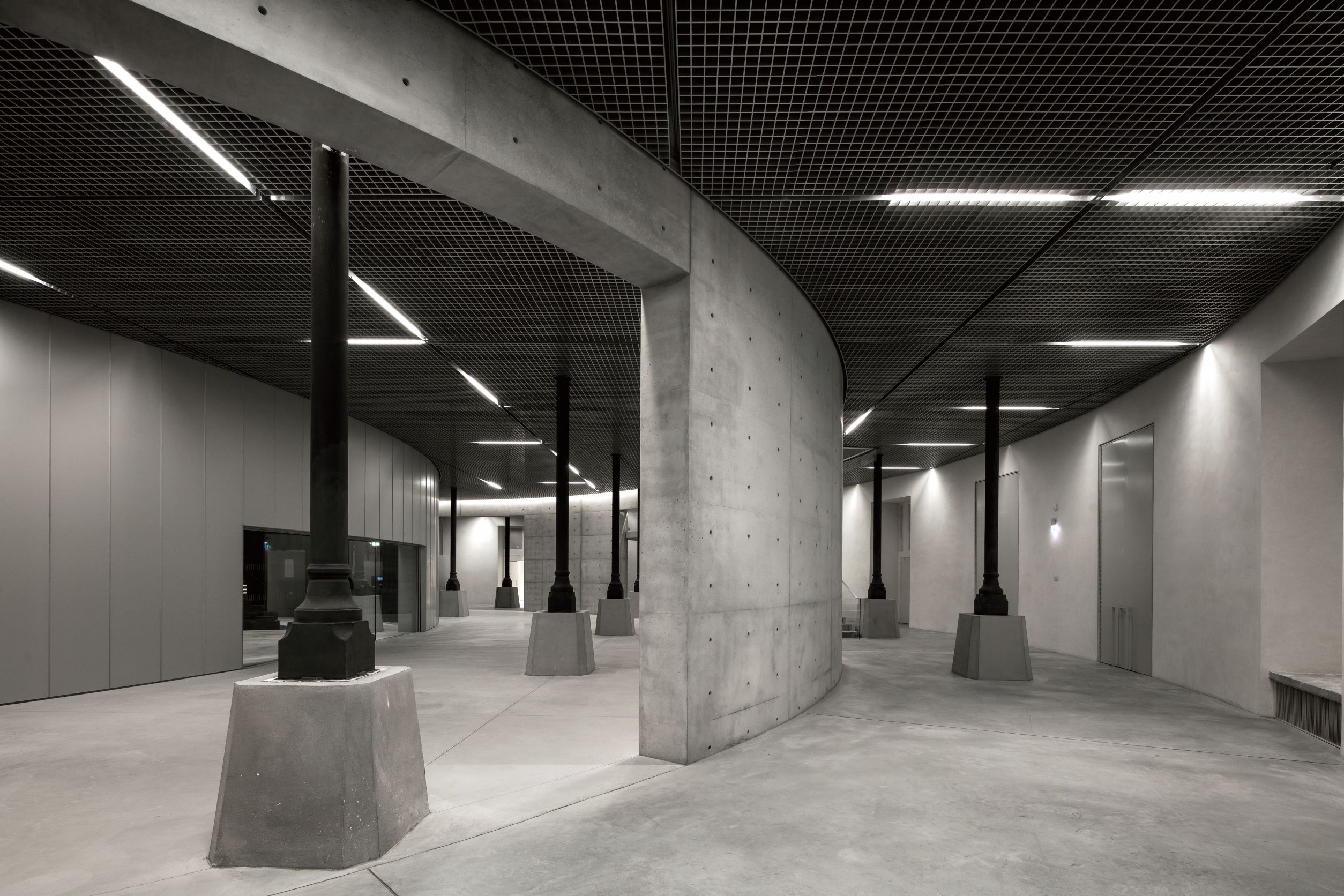 延伸至地下楼层的清水模圆柱设计，还加入了黑色柱列作为支撑和装饰。 ( © Patrick Tourneboeuf )
