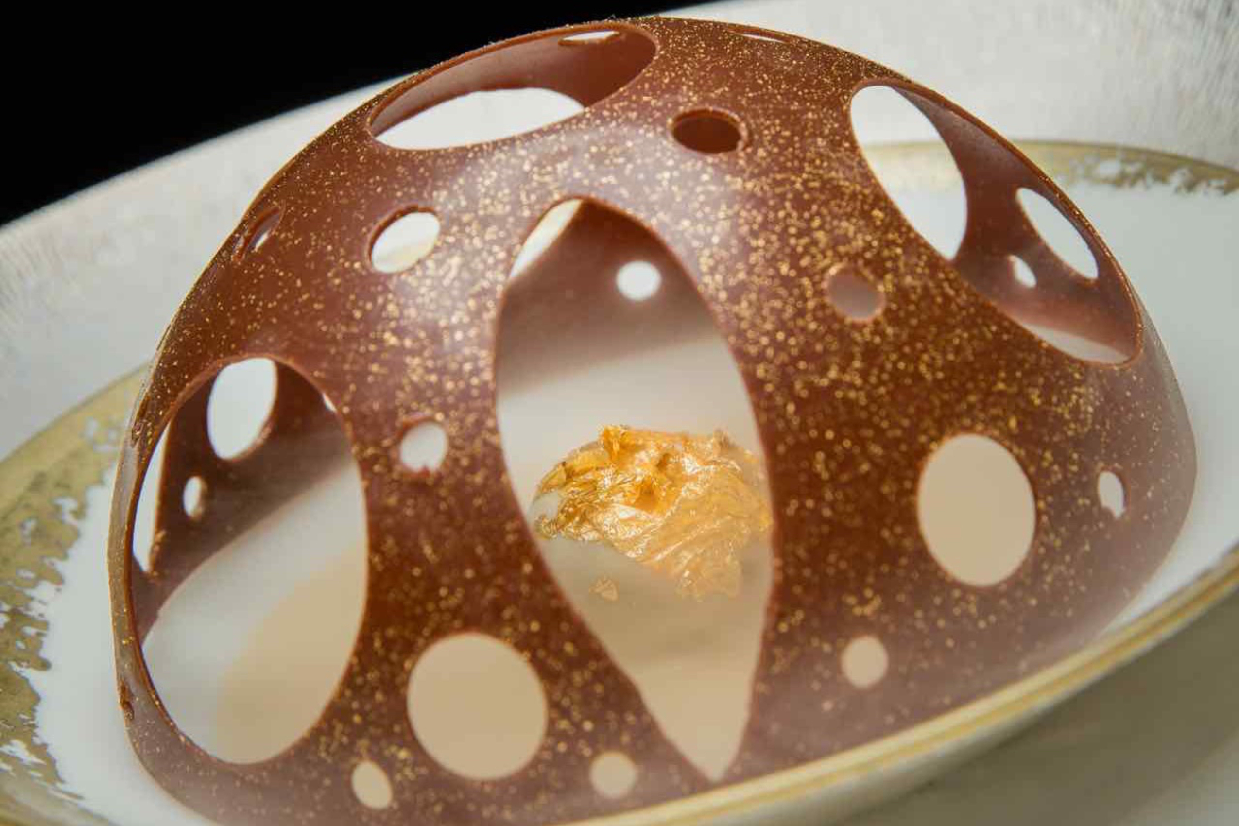 造型如同天巢圆顶的“经典朱古力慕斯圆顶伴特色啫喱”，大片金箔与干冰效果将这款甜点营造得很有气势。