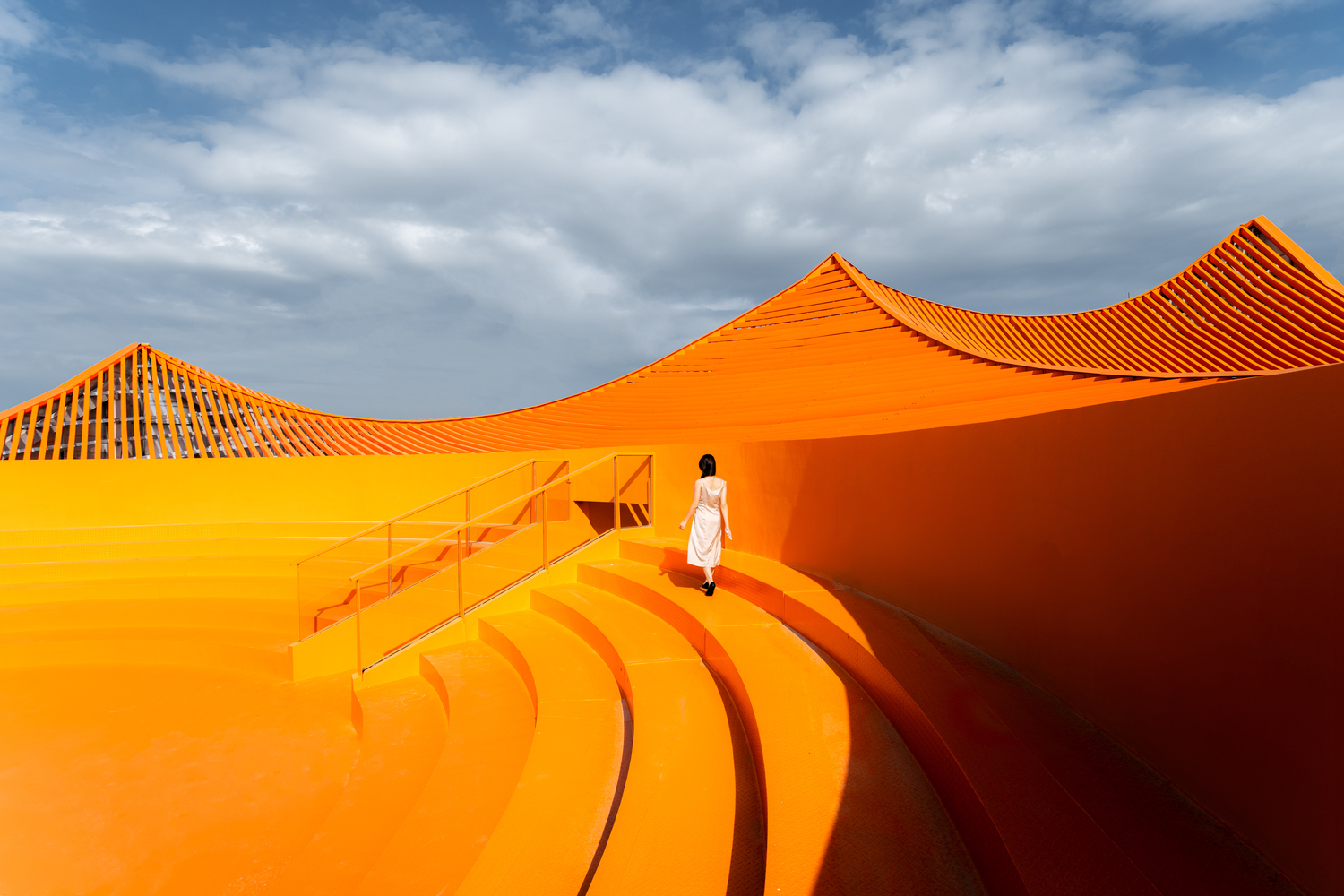 色彩鲜艳的橘红色屋顶上，特别设计有一座弧形露天剧场。