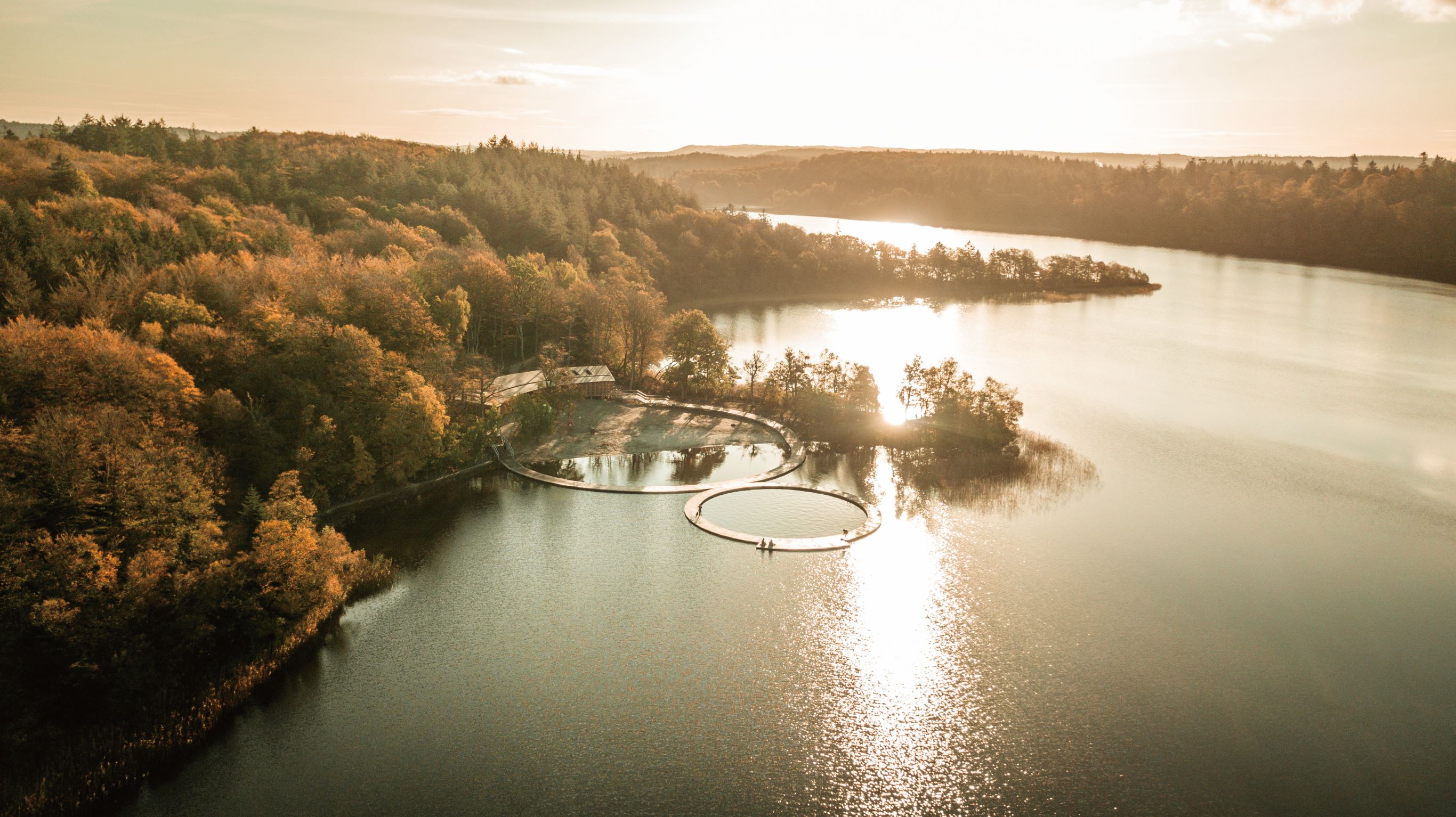 座落在湖光山色间的 Eastern and Western Bathing Resort，以环形桥梁框出大湖泊中的小湖泊，让整个浴场自然融入周遭景观中。