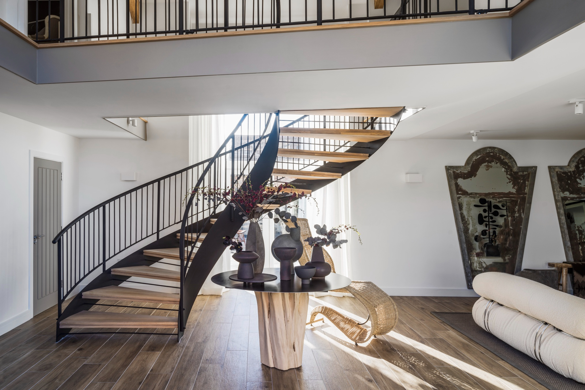 现代感的白色巨型回旋吊灯和优雅镂空的黑色螺旋楼梯、栏杆，形成鲜明对比，既现代又复古。