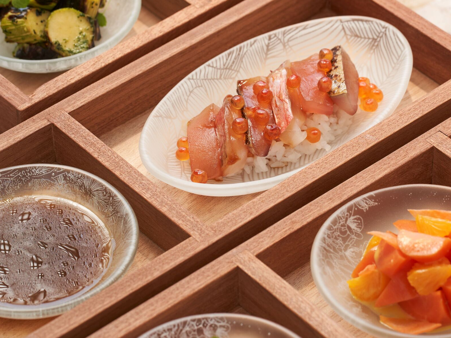 以木格托盘和玻璃餐盘装盛的 Mory Sacko at Louis Vuitton 午餐餐点。