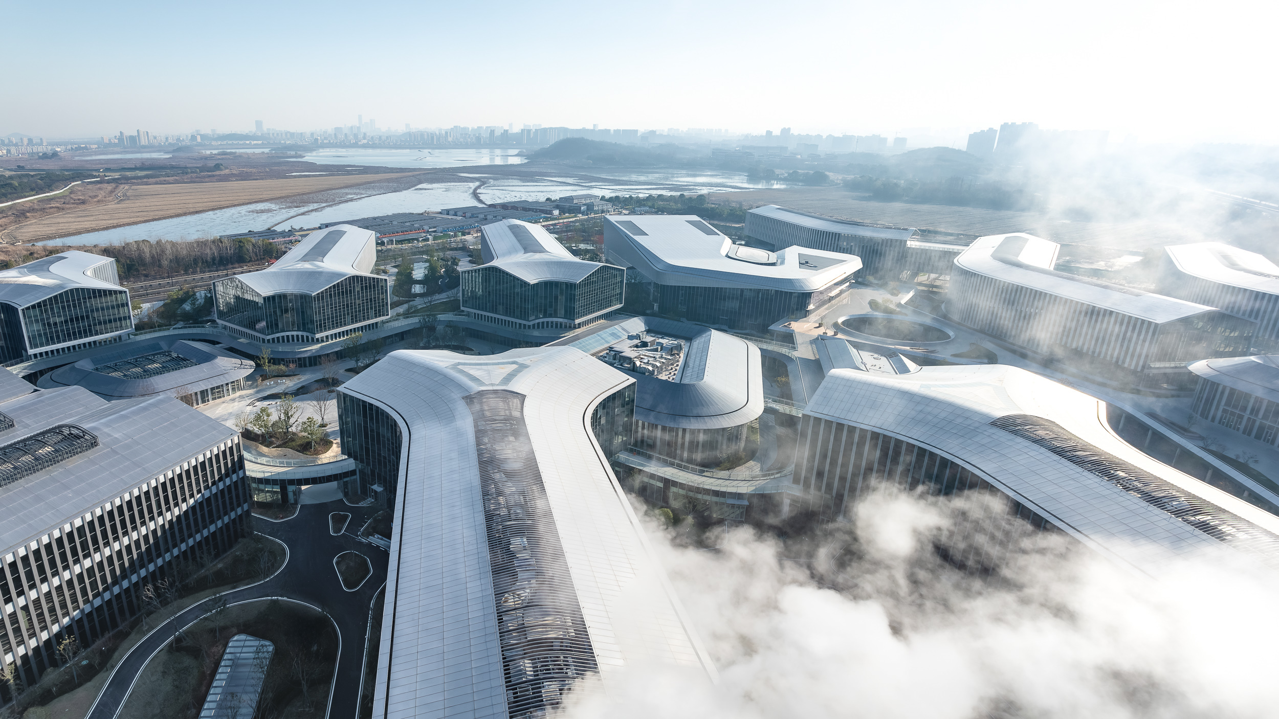 園區以菩提葉脈為靈感，兩側建築沿中央景觀軸線向外伸展，將湖景與河景引入內部。