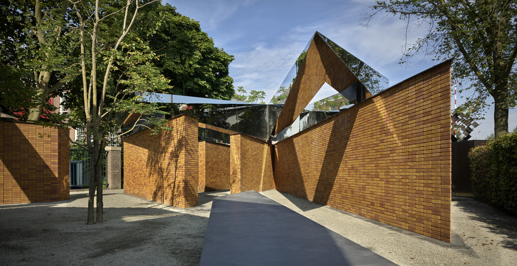 Dutch Holocaust Memorial of Names 在迷宫般的砖墙通道上，架设有代表纪念一词的不锈钢几何量体。